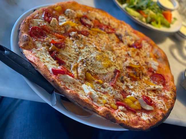 Photo of a Pollo Forza pizza from Pizza Express. There is a pizza wheel slide between the pizza and the plate.