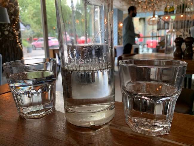 A photo taken in Megans Clapham Common of a bottle of water in between two water glasses.