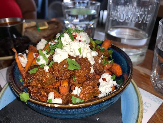 a photo of a bowl of Lamb and feta sweet potato fries from Megans Clapham Common