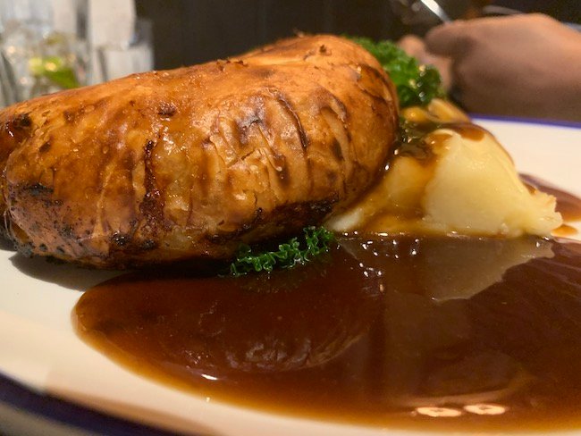 A low-down close-up photo of the pie from The Abbeville Clapham with a pool of gravy taking up much of the bottom of the screen.