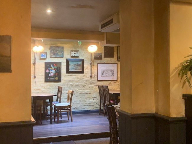 a photo of the interior of The Abbeville Clapham with pictures mounted on the wall.